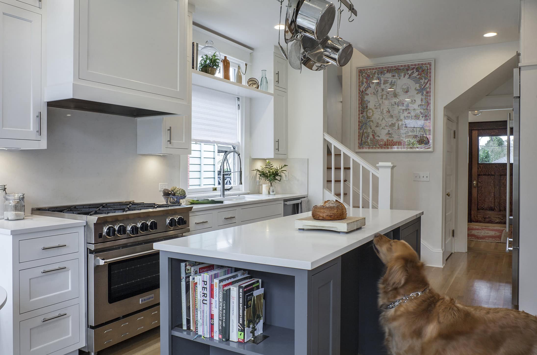 modern craftsman style kitchen with blue island, white cabinets, open shelving, and pot rack