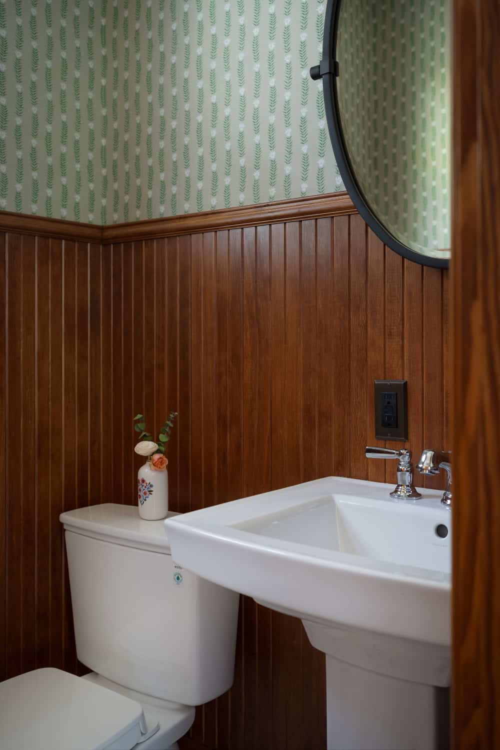 A classic power bathroom with rich wood wainscot and decorative wallpaper.