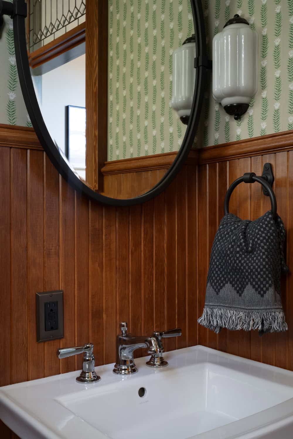 A classic power bathroom with rich wood wainscot and decorative wallpaper.