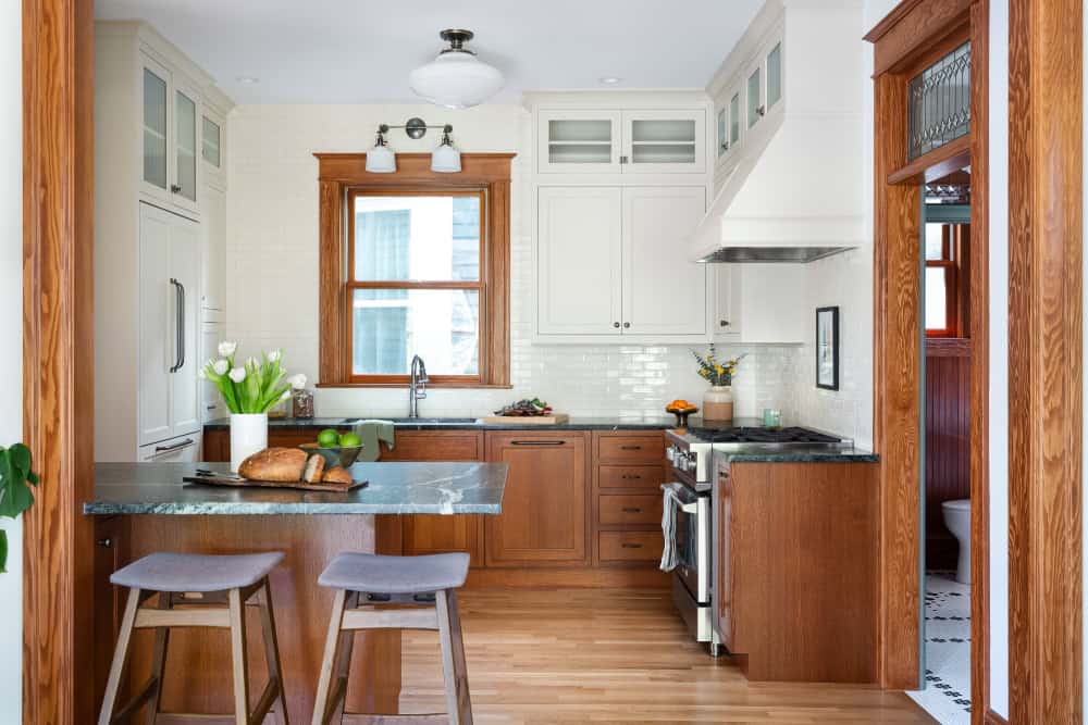 1902 Craftsman kitchen with warm wood lower cabinets, soapstone countertops, and crisp white upper cabinets with custom range hood.