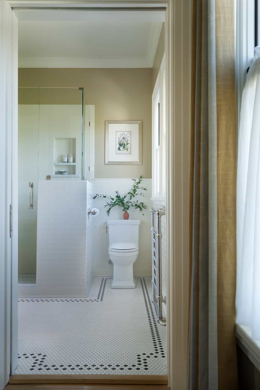 Warm neutral bathroom with period appropriate fixtures including plumbing, lighting, tile, cabinetry, and wainscot.