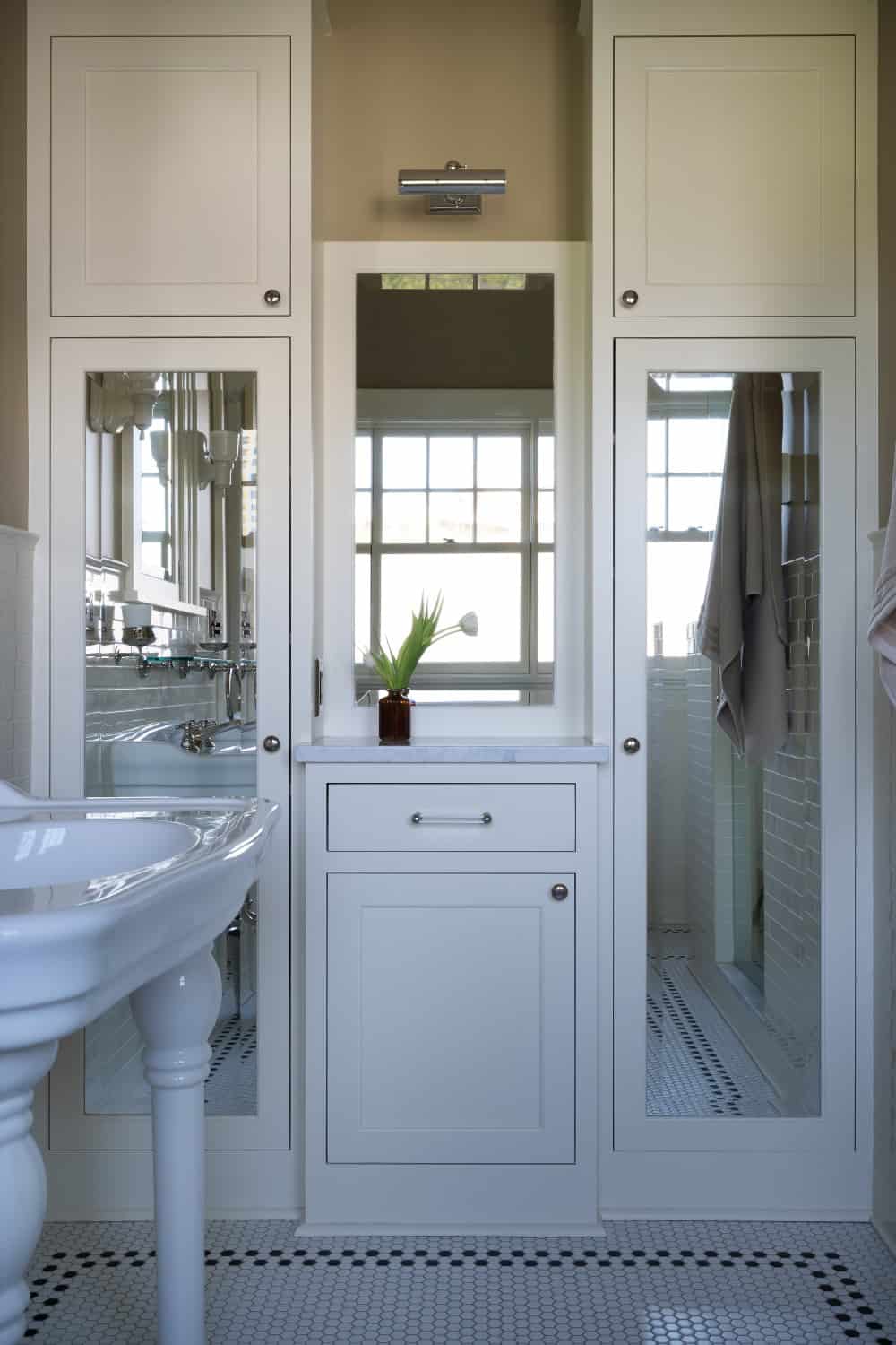 Warm neutral bathroom with period appropriate fixtures including plumbing, lighting, tile, cabinetry, and wainscot.