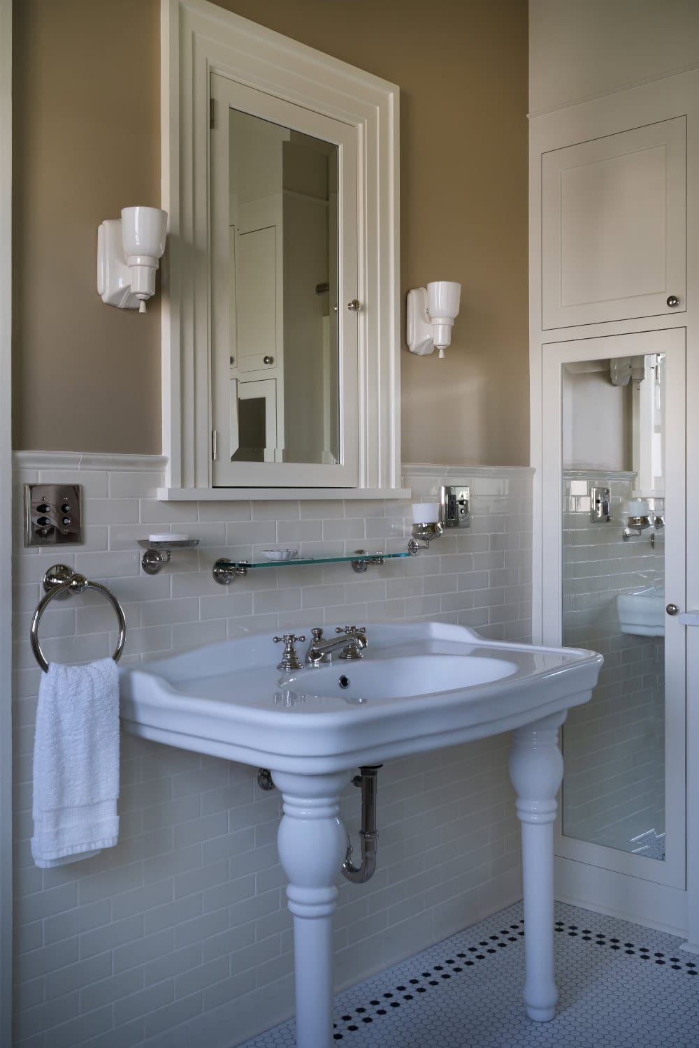 Warm neutral bathroom with period appropriate fixtures including plumbing, lighting, tile, cabinetry, and wainscot.